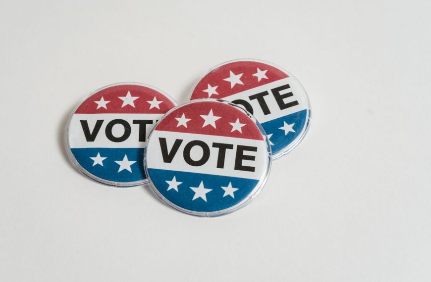 Red, white, and blue voting badges promoting elections on a clean white background.